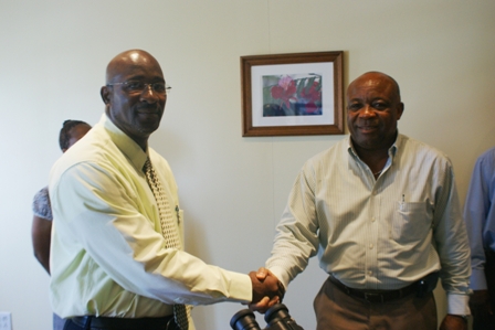 (L-R) Pastor of the Seven Day Adventist Church in Charlestown Jerry Languedoc shaking hands with Minister of Health in the Nevis Island Administration Mr. Hensley Daniel while presenting him with gifts on behalf of his church